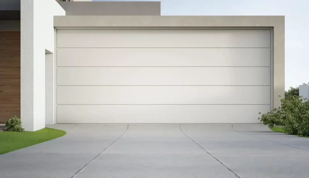 Closed white garage door with horizontal panels, bordered by a driveway and small shrubs on each side.